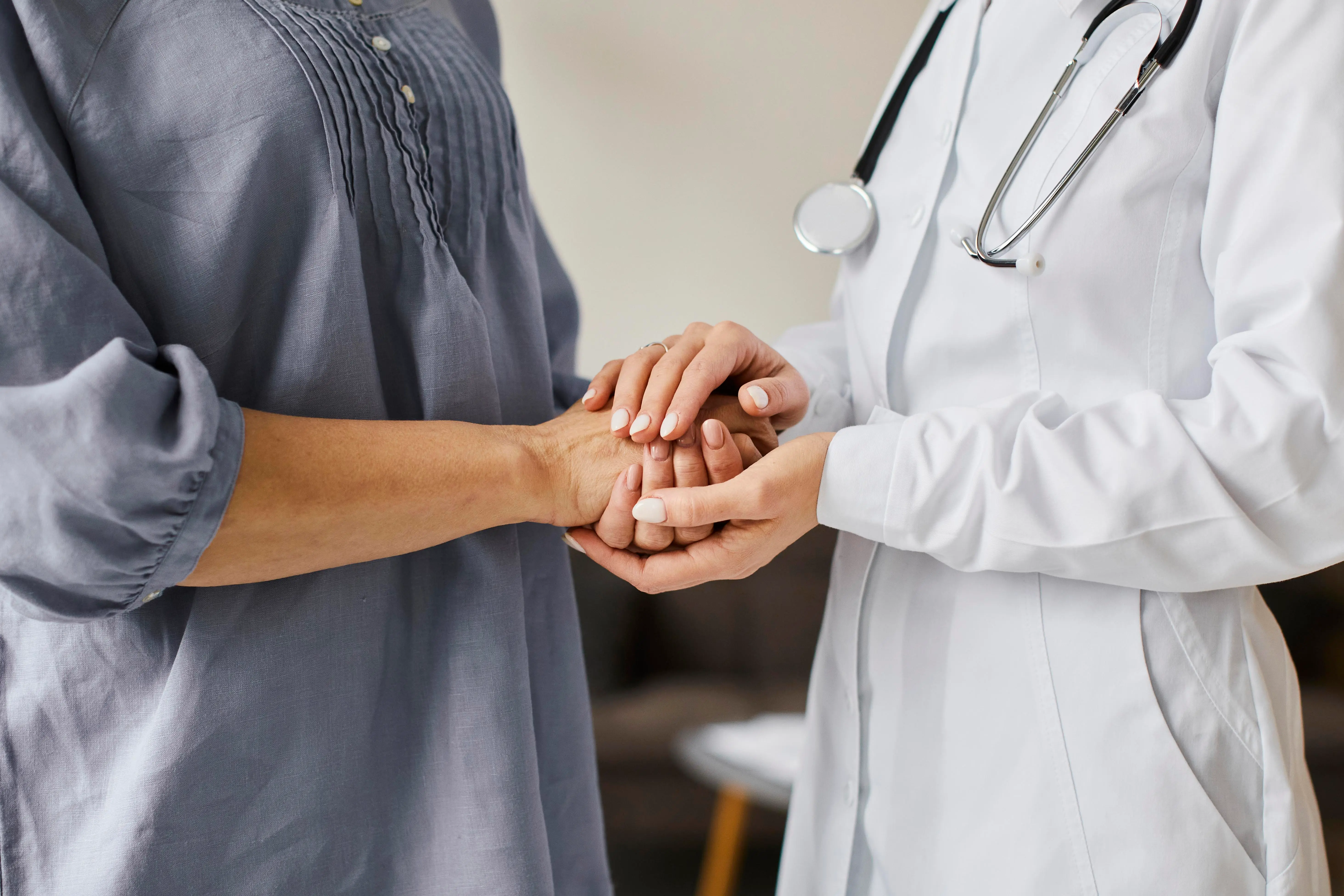 Ärztin hält Hand einer Patientin
