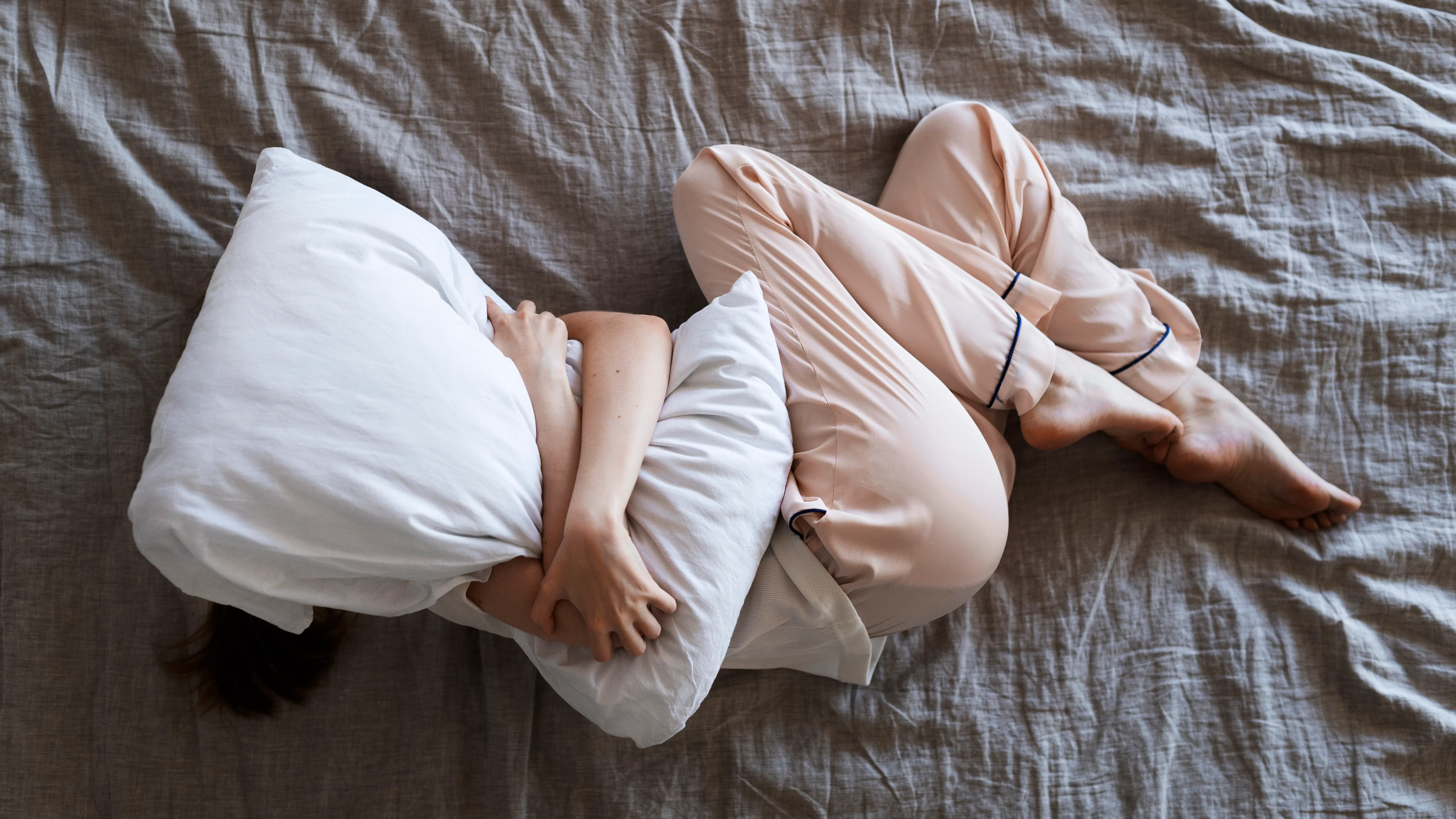 Frau im Bett mit Kissen über dem Kopf