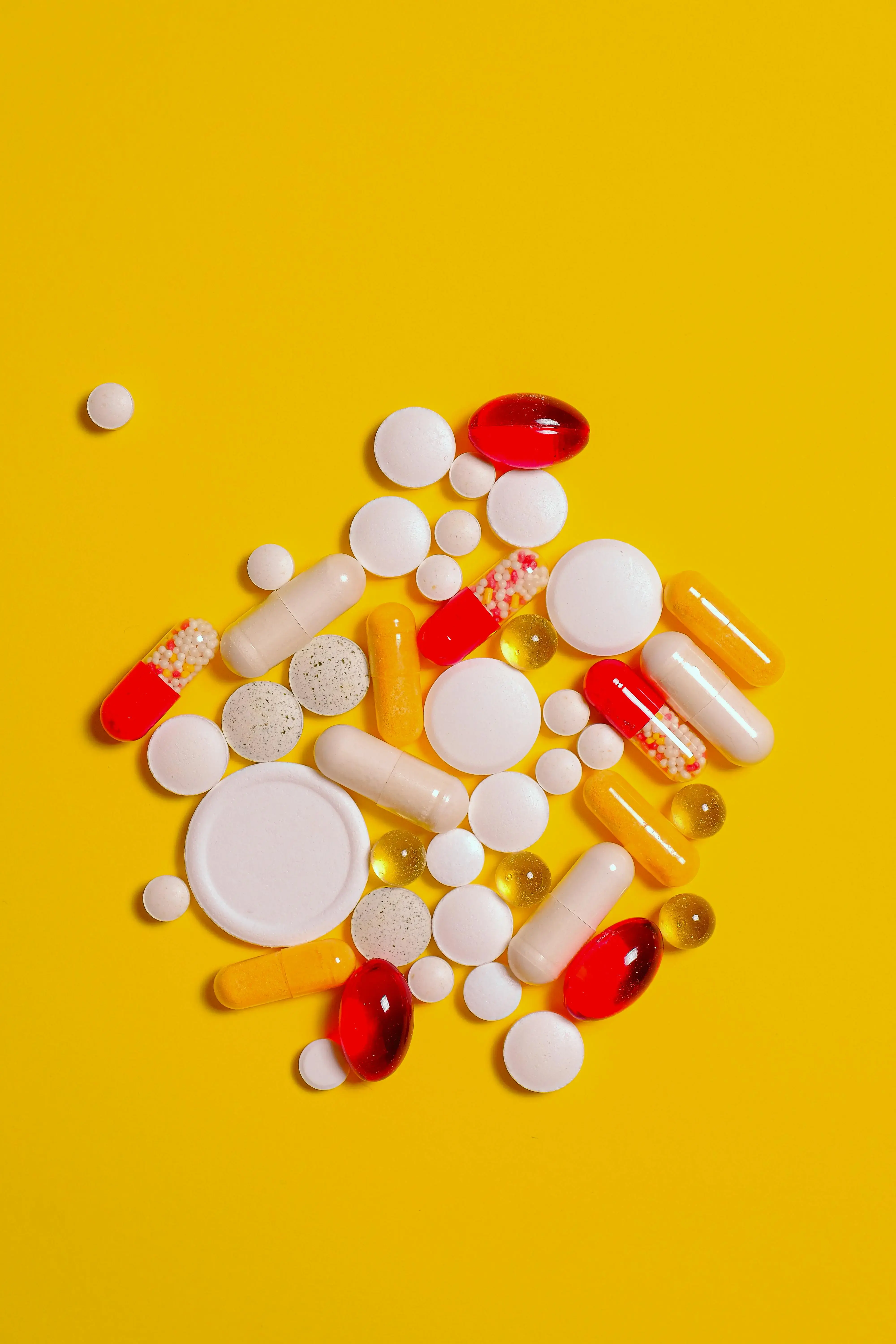 verschiedene Pillen und Tabletten auf gelbem Untergrund